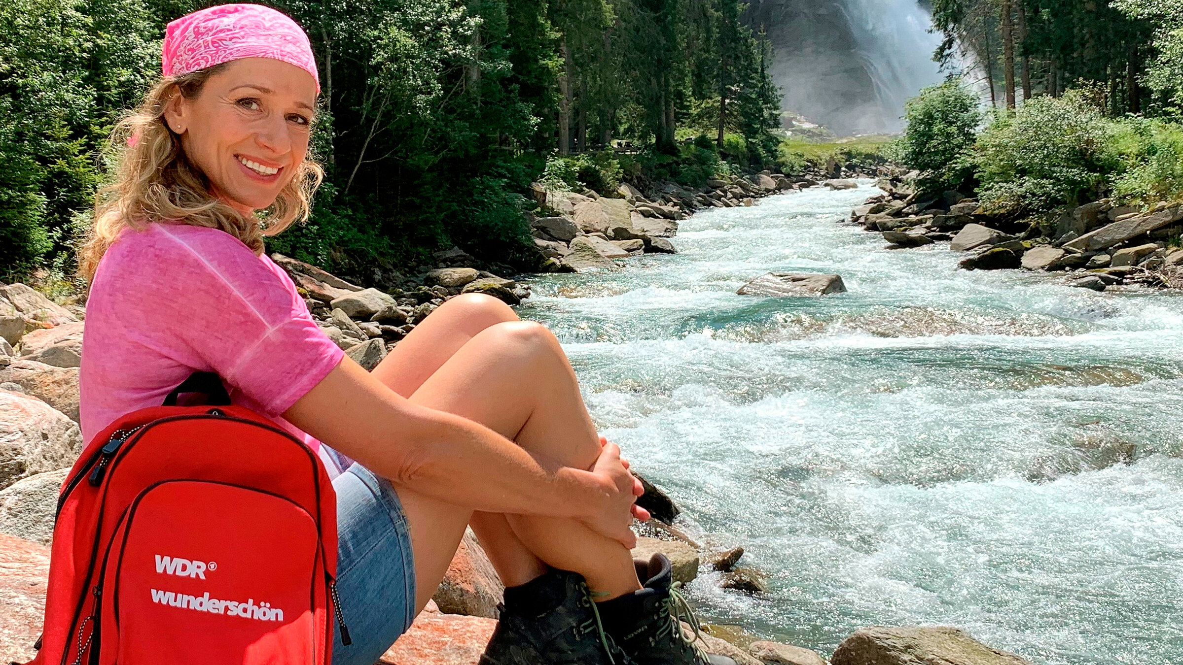 "Gipfelglück im Zillertal": Tamina Kallert am Ufer der Krimmler Ache vor Österreichs höchsten Wasserfällen, die Krimmler Wasserfälle.