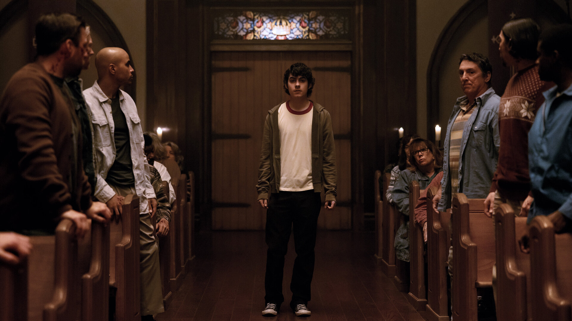 "Hysteria! - Die Nacht der Erlösung": Dylan (Emjay Anthony) steht allein im Mittelgang einer vollbesetzten Kirche, umgeben von Menschen (Komparsen), die ihn aufmerksam ansehen.