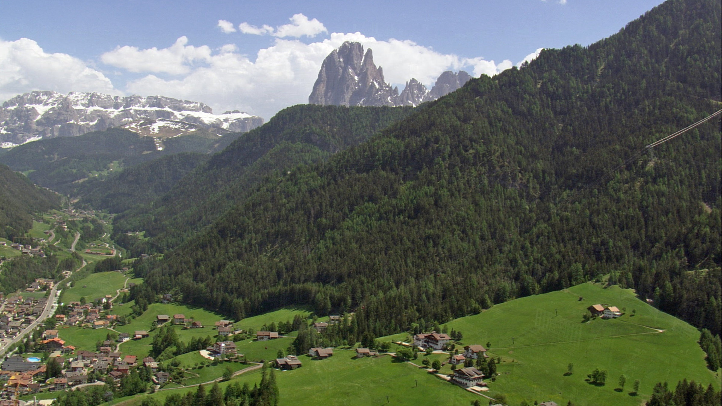 "Norditalien von oben": Grüne und alpine Berglandschaft der Dolomiten mit schroffen Felsen im Hintergrund.