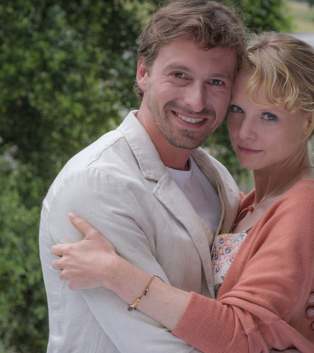 "Rosamunde Pilcher: Wenn Fische lächeln": Ray (Ben Blaskovic) und Liz (Friederike Ott) stehen Arm in Arm vor einem großen Anwesen und lächeln in die Kamera.