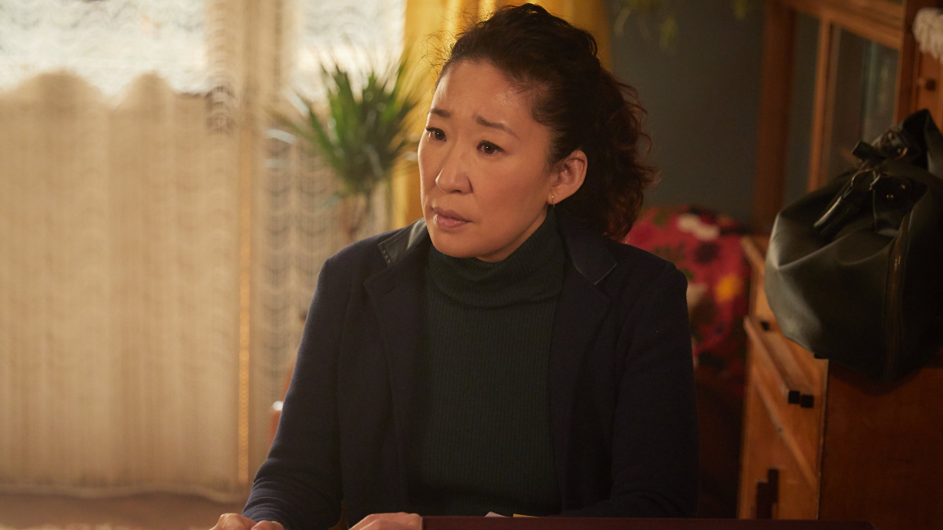 "Killing Eve - Ich will nicht frei sein": Eve (Sandra Oh) sitzt an einem Tisch auf dem eine Box mit Fotos und andern Kleinigkeiten liegt. Dabei schaut sie verständnisvoll in die Ferne.
