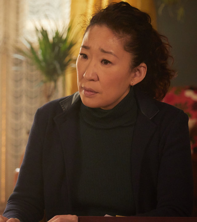 "Killing Eve - Ich will nicht frei sein": Eve (Sandra Oh) sitzt an einem Tisch auf dem eine Box mit Fotos und andern Kleinigkeiten liegt. Dabei schaut sie verständnisvoll in die Ferne.