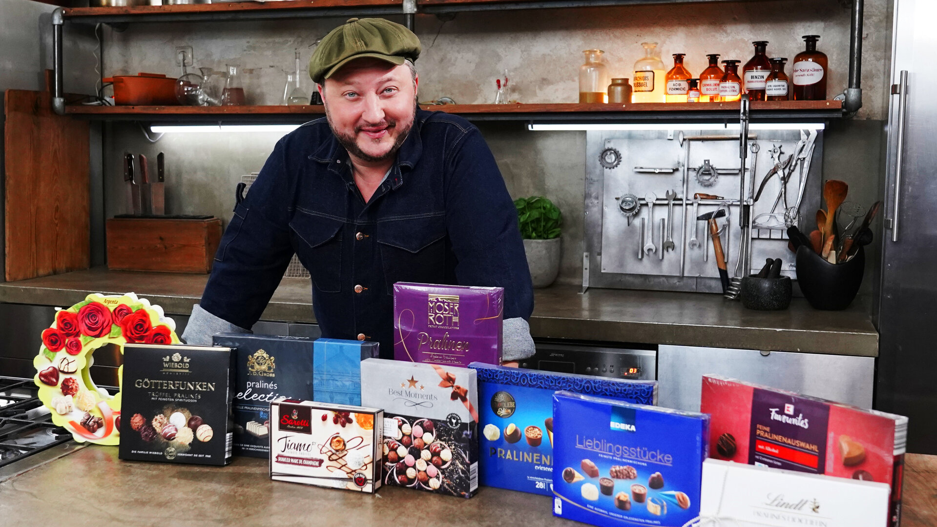 "besseresser: Falsche Feinkost-Versprechen - Sebastian Lege packt aus": Sebastian Lege steht hinter verschiedenen Pralinen-Verpackungen.
