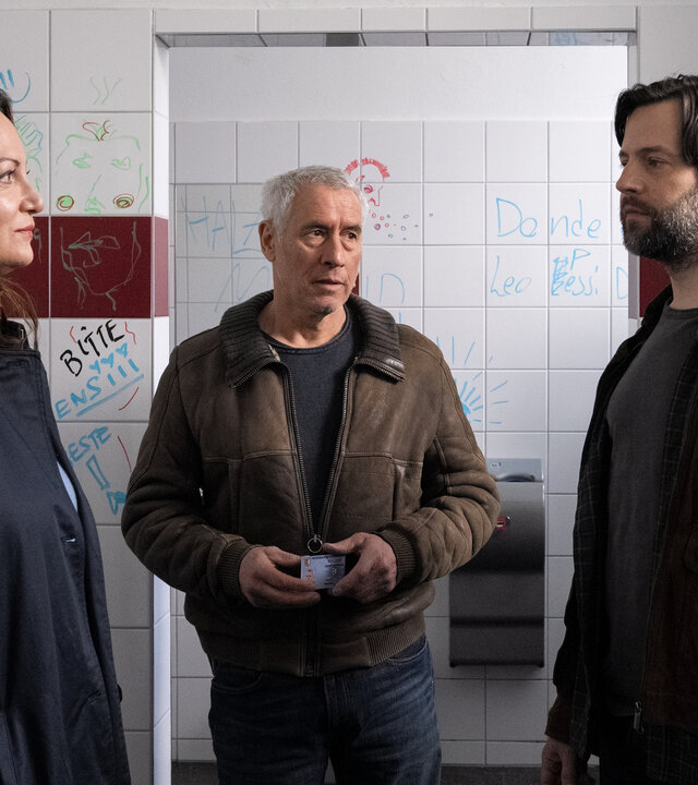 "Unter anderen Umständen - Dominiks Geheimnis": Jana Winter (Natalia Wörner), Matthias Hamm (Ralph Herforth) und Gustav Mikkelsen (Richard Ulfsäter) stehen zusammen in einer Schülertoilette.