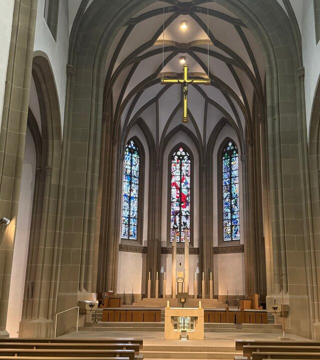 "Katholischer Gottesdienst - In der Liebe Gottes?!": Innenansicht auf den Altar und die Buntfenster der Stadtpfarrkirche Herz Jesu in Bad Kissingen.