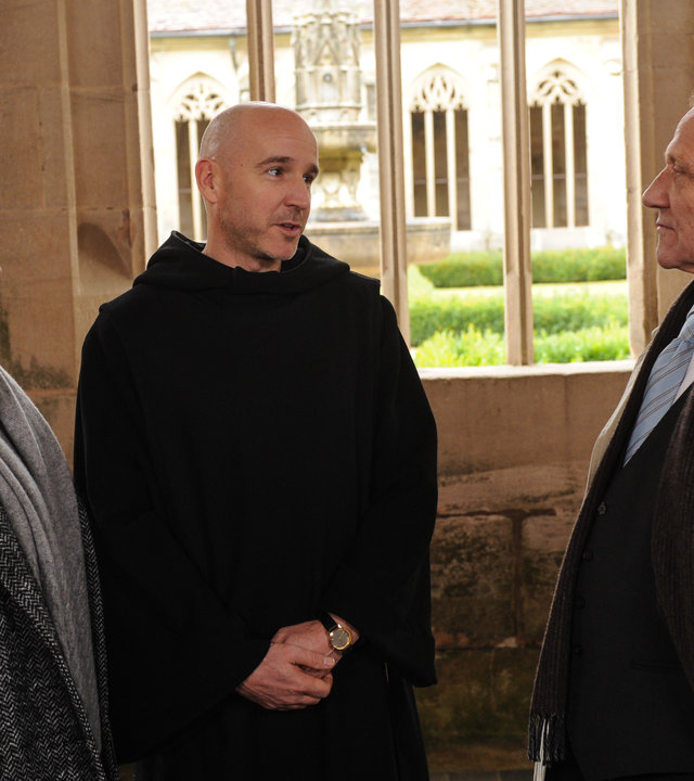 "SOKO Stuttgart - Die Seele ist unsterblich": In einem Klostergang reden Selma Kirsch (Yve Burbach) und Michael Kaiser (Karl Kranzkowski) mit Pater Ignatius (Paul Herwig), der in ihrer Mitte steht.