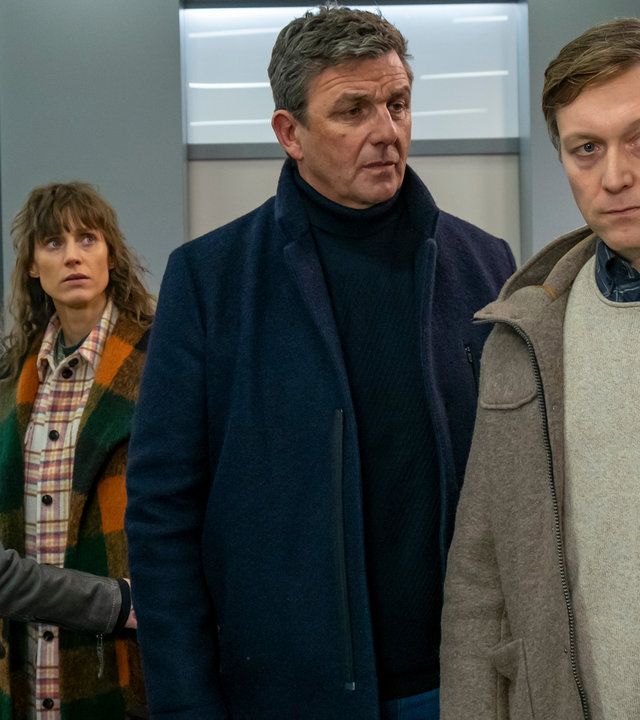 "Der Bergdoktor: Was bleibt (2)": Im Krankenhausflur stehen Dr. Martin Gruber (Hans Sigl) und Christoph Angerer) nachdenklich zusammen. Im Hintergrund blickt Katharina Bichler (Sophie Lutz) fassungslos zu den beiden, während Maja (Lorna zu Solms) sie am Arm festhält.