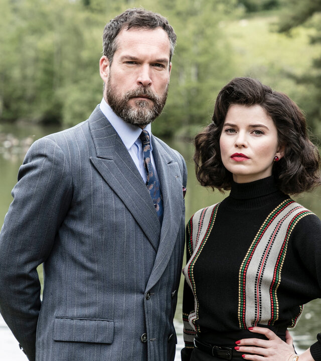 "Father Brown - Der Familienwettstreit": Die Konkurrenten Hercule Flambeau (John Light) und Marianne Delacroix (Gina Bramhill) stehen am See.
