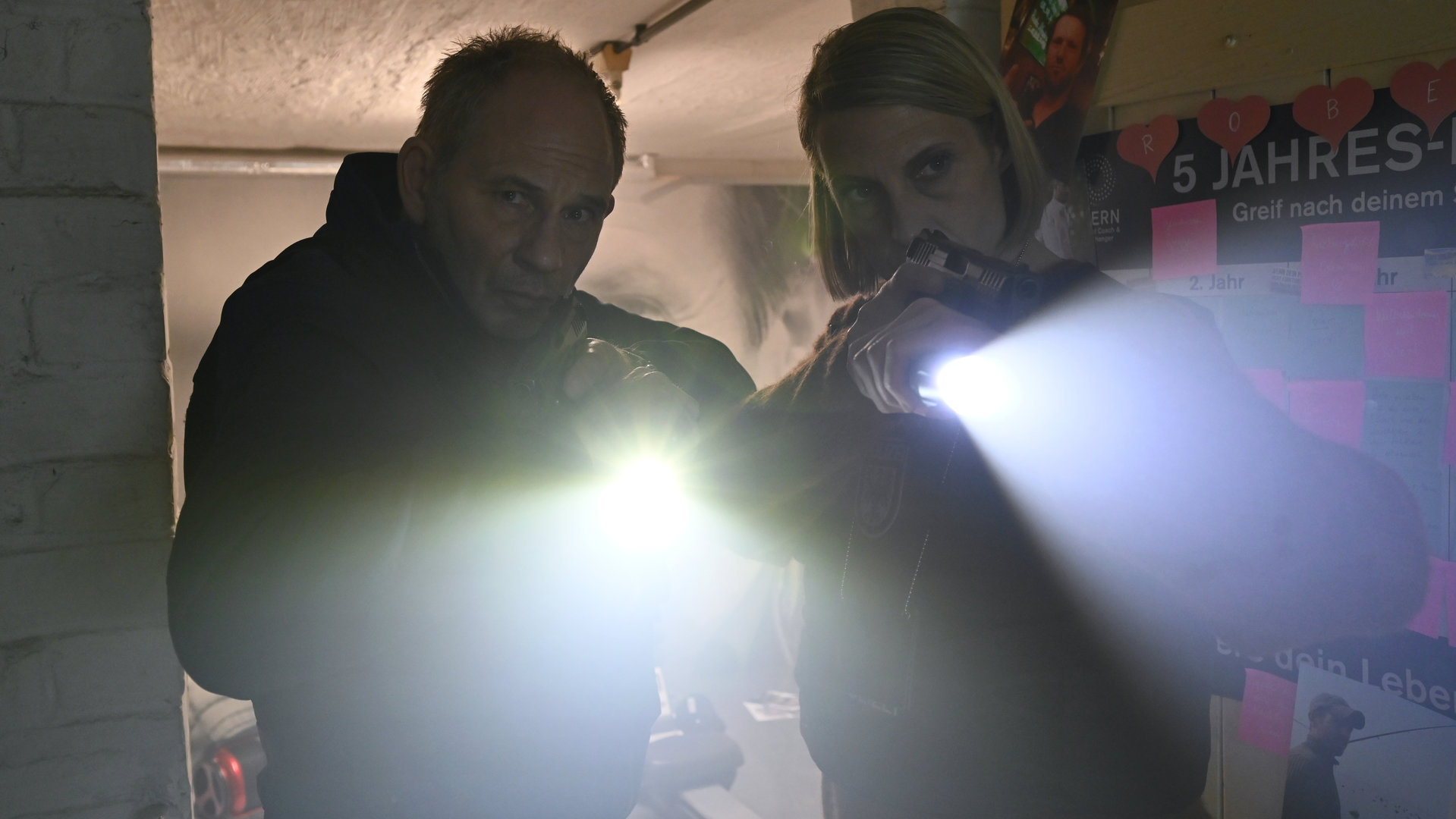 "SOKO Potsdam - Raumwunder": In einer Kellertür stehen Tamara Meurer (Anja Pahl) und Bernhard Henschel (Michael Lott). Beide leuchten mit einer Taschenlampe in Richtung Kamera und halten eine Pistole in der Hand.