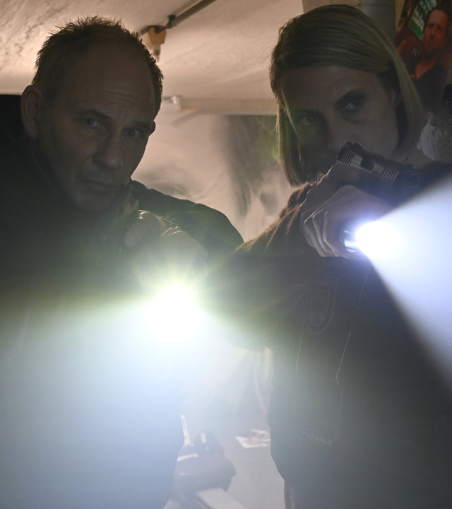 "SOKO Potsdam - Raumwunder": In einer Kellertür stehen Tamara Meurer (Anja Pahl) und Bernhard Henschel (Michael Lott). Beide leuchten mit einer Taschenlampe in Richtung Kamera und halten eine Pistole in der Hand.
