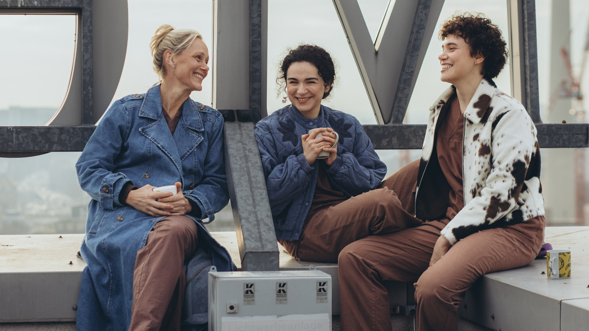 "PUSH - Und dann kamst du": Anna (Anna Schudt), Nalan (Mariam Hage) und Greta (Lydia Amasko) sitzen gemeinsam auf dem Klinikdach. Alle drei sind glücklich und lächeln.