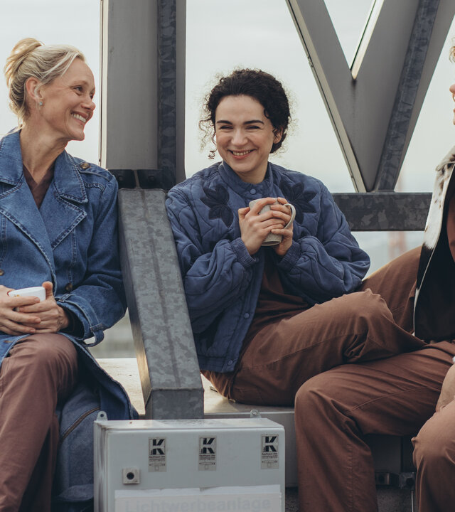"PUSH - Und dann kamst du": Anna (Anna Schudt), Nalan (Mariam Hage) und Greta (Lydia Amasko) sitzen gemeinsam auf dem Klinikdach. Alle drei sind glücklich und lächeln.