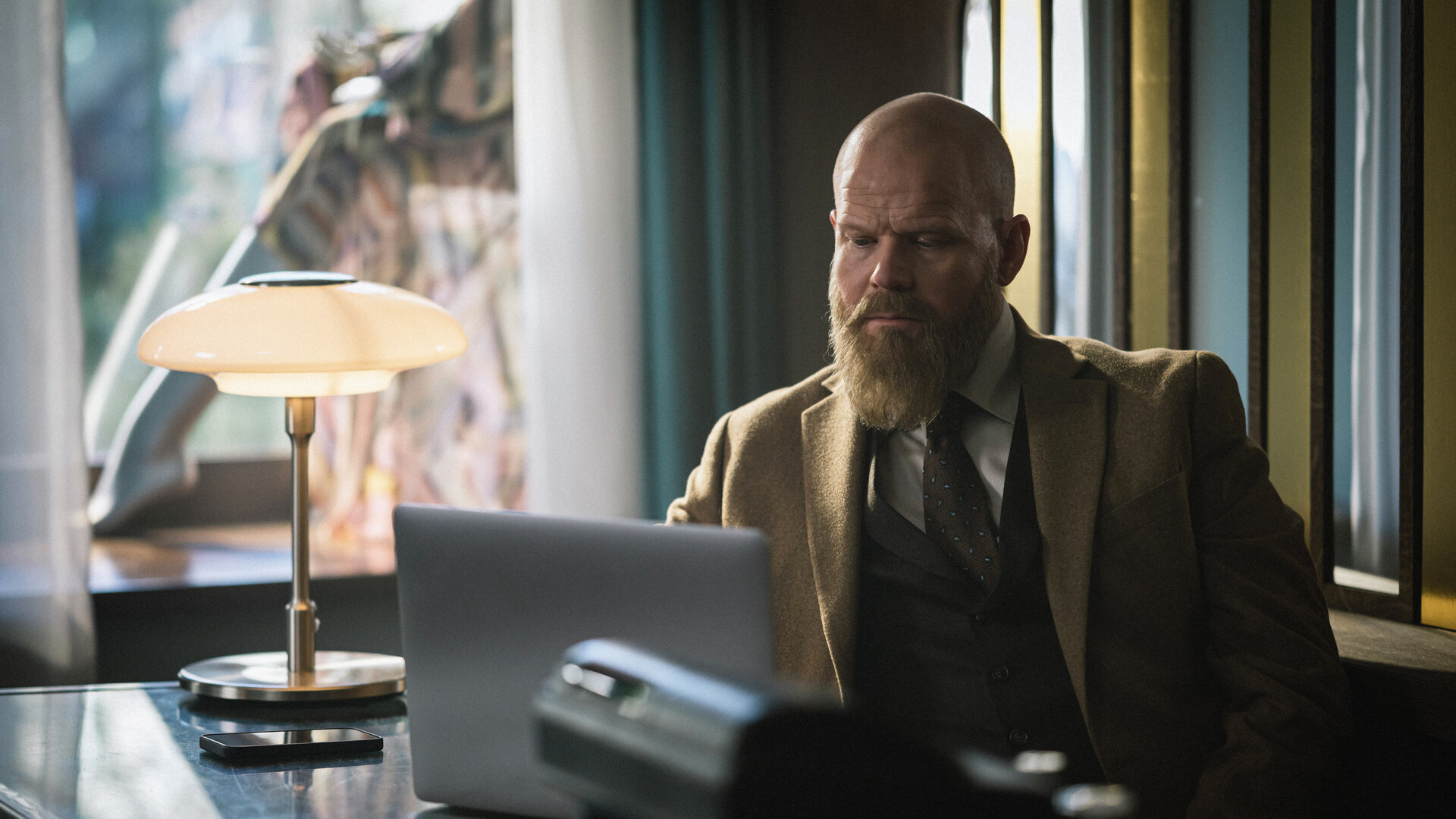 "Toxic Tom - Das Ende von Tom": Der Modeverkäufer Tom Hallsténsen (Anders Baasmo) sitzt am Tresen seiner Damenboutique und blickt auf einen aufgeklappten Laptop.