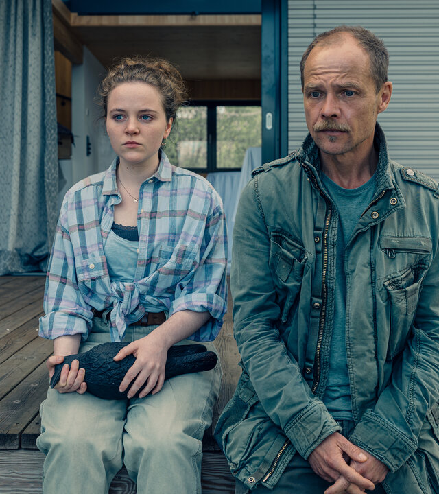"Die Toten vom Bodensee - Das Geisterschiff": Lenka Bergdorf (Alice Prosser) und Micha Oberländer (Matthias Koeberlin) sitzen nebeneinander auf einem Bootssteg. Lenka Bergdorf hält eine Figur in der Hand.
