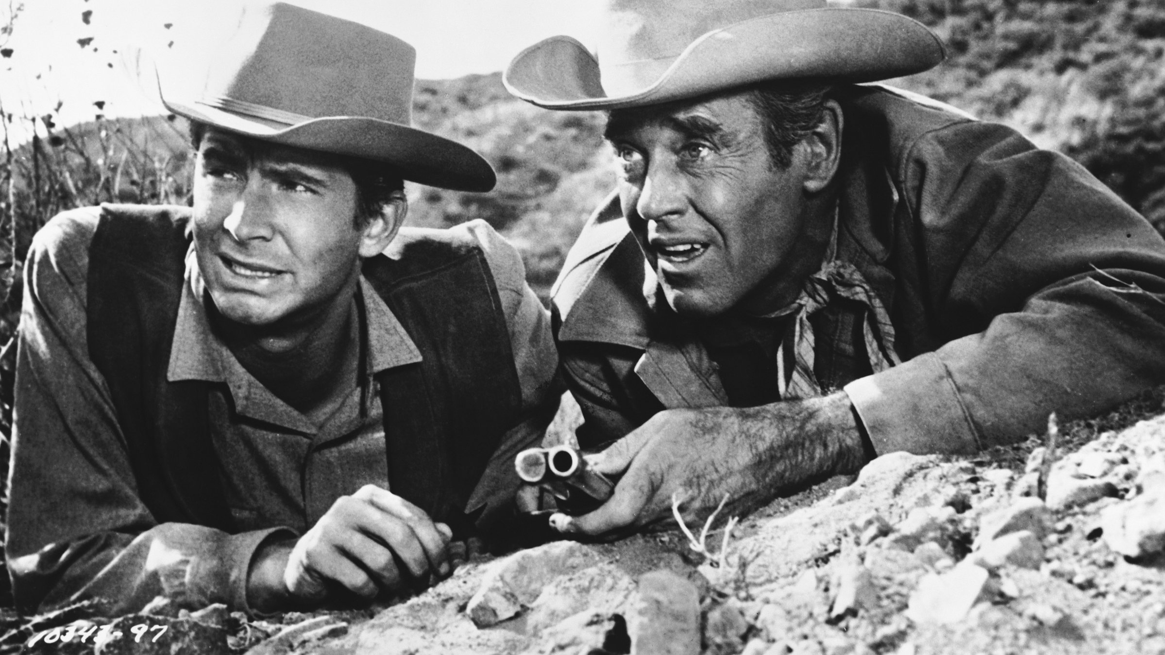 "Stern des Gesetzes": Ben Owens (Anthony Perkins) und Morg Hickman (Henry Fonda) ‎liegen an einem felsigen Hang hinter einer leichten Bodenerhebung und fixieren angespannt ein Ziel. Beide tragen Westernhüte, Hickman hat ein Gewehr bei sich.