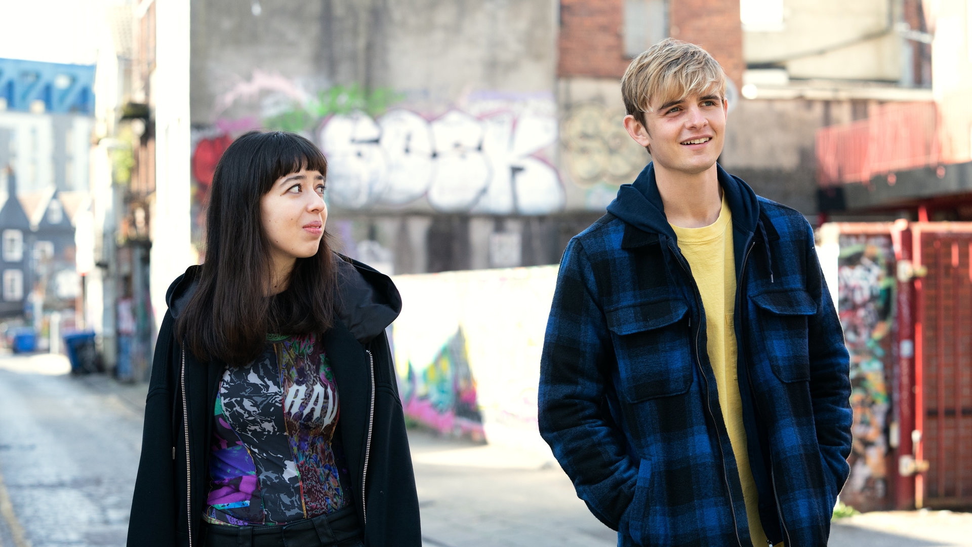 "Alex Rider - Bedrohung": Kyra (Marli Siu) und Alex (Otto Farrant) laufen eine Gasse entlang. Während Alex fröhlich in die Ferne blickt, schaut Kyra zu ihm rüber.