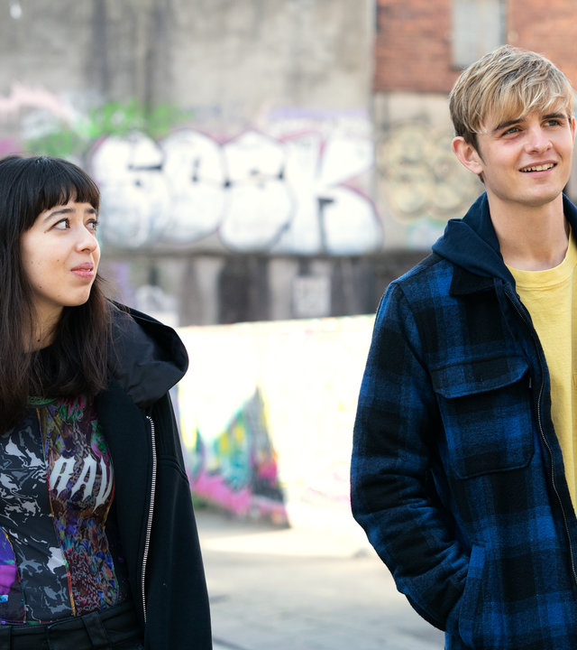 "Alex Rider - Bedrohung": Kyra (Marli Siu) und Alex (Otto Farrant) laufen eine Gasse entlang. Während Alex fröhlich in die Ferne blickt, schaut Kyra zu ihm rüber.