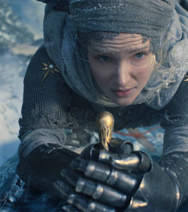 "Der Herr der Ringe: Die Ringe der Macht - Schatten der Vergangenheit": Galadriel (Morfydd Clark) hält einen Schwergriff umklammert. Sie trägt eine Rüstung und ein Kopftuch. Hinter ihr liegt eine eisige Landschaft.