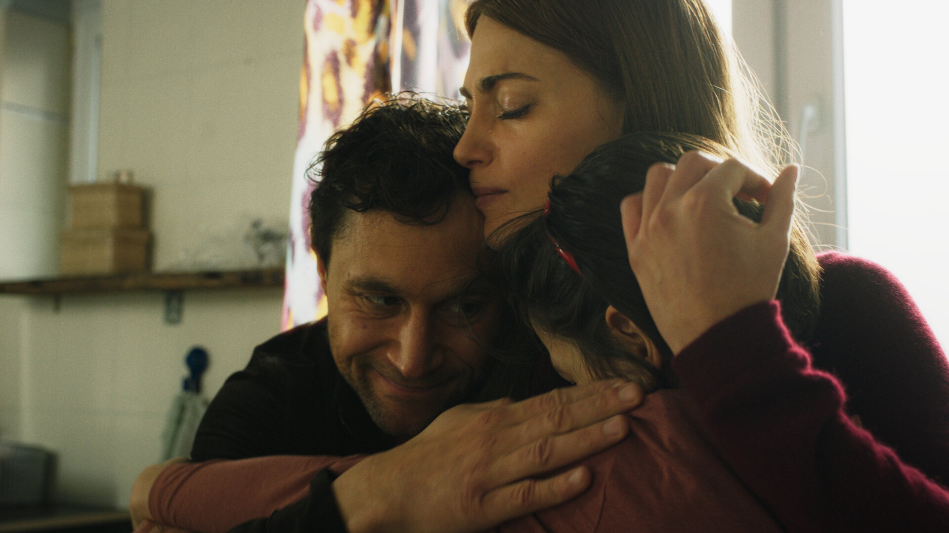 "Bauchgefühl - Wieder Lena": Lena (Laura Berlin) hat ihren Mann Felix (Ludwig Trepte) und ihre Tochter Greta (Lilo Nika Daners) fest im Arm. Ihre Augen sind geschlossen, ihre Hand liegt an Gretas Kopf. Felix Arm drückt Lena und Greta noch enger an sich. Er schaut Greta liebevoll an.
