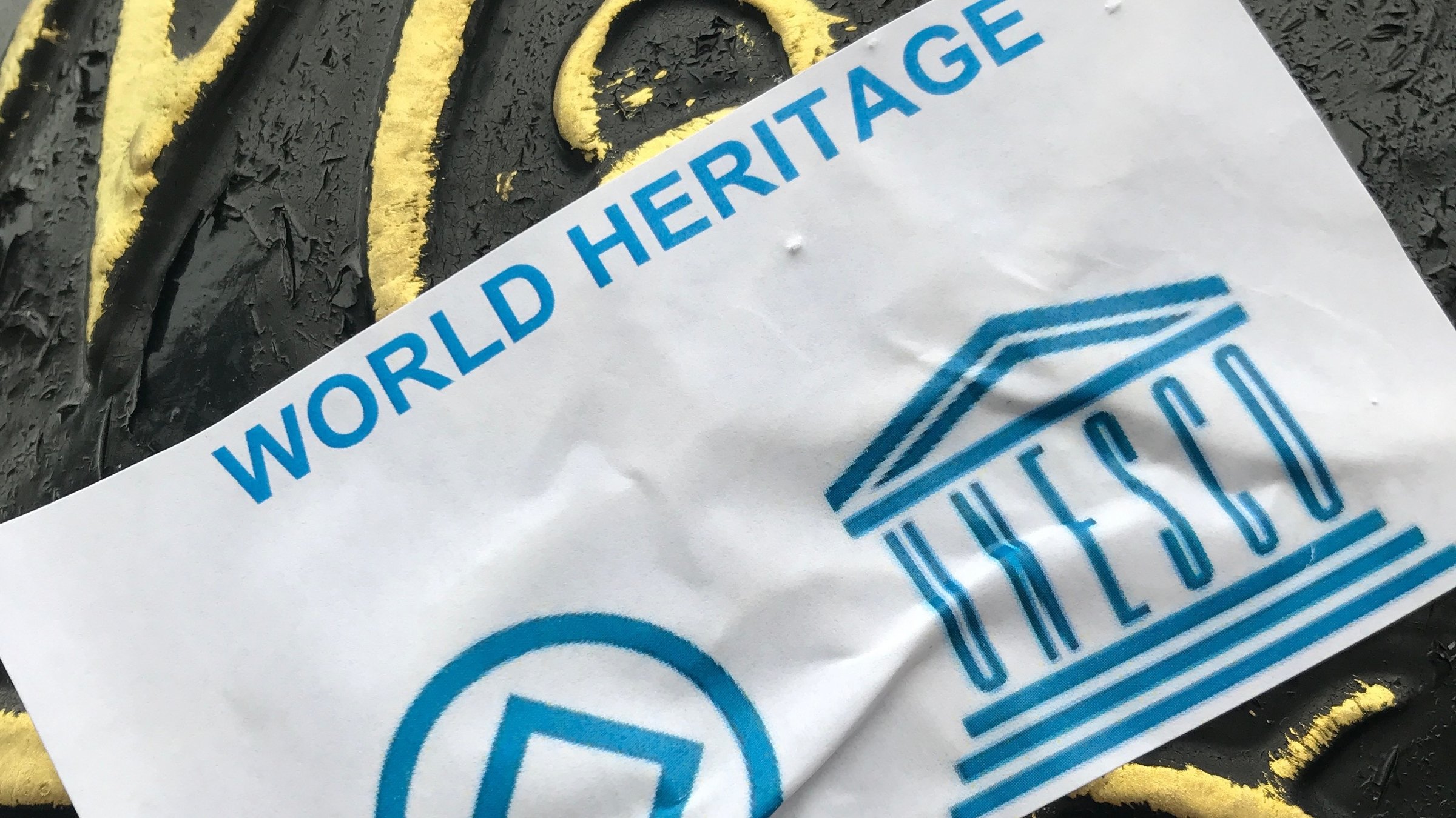 „Welterbe in Gefahr – Wie viel Macht hat die UNESCO noch?“: Das World Heritage Emblem und das Logo der Unesco nebeneinander.