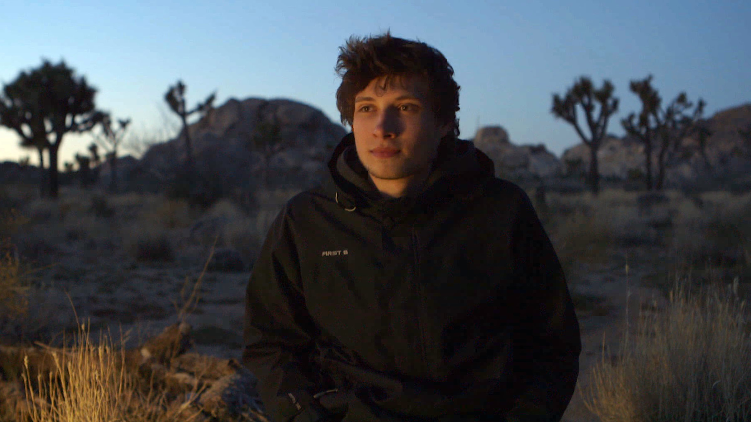 "Ab 18! - Mein letztes Video": Nahaufnahme eines jungen Mannes, der in der Abenddämmerung in der kalifornischen Wüste sitzt.