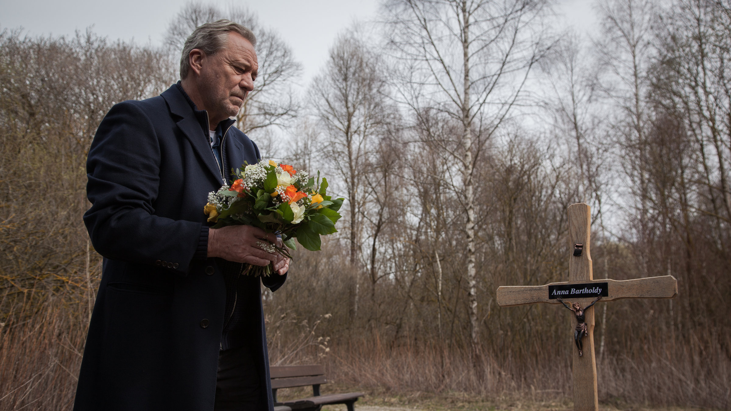 "SOKO M&uuml;nchen - Katharinas Albtraum": Arthur Bauer (Gerd Silberbauer) h&auml;lt einen Blumenstrau&szlig; in den H&auml;nden und steht vor dem Grab von Anna Bartholdy.