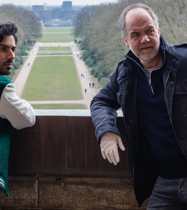 "SOKO Hamburg - Das Fenster zum All": Luiz Vieira dos Santos (Thiago Braga de Oliveira) und Oskar Schütz (Marek Erhardt) stehen auf einer Aussichtsplattform und blicken nachdenklich nach rechts. Luiz hat sich mit den Armen auf die Brüstung der Plattform gestützt. Oskar Schütz lehnt mit dem Rücken an der Brüstung und trägt weiße Gummihandschuhe.