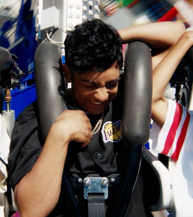 "After Benjamin: Neverland": Espen (Magnus Johan Tenfjord), Omer (Benjamin Ahmed) und Jama G (Nickolai Sødal Kabanda) sitzen nebeneinander in einer fahrenden Achterbahn. Sie halten sich an den Sicherheitsbügeln fest und haben sichtlich Spaß.