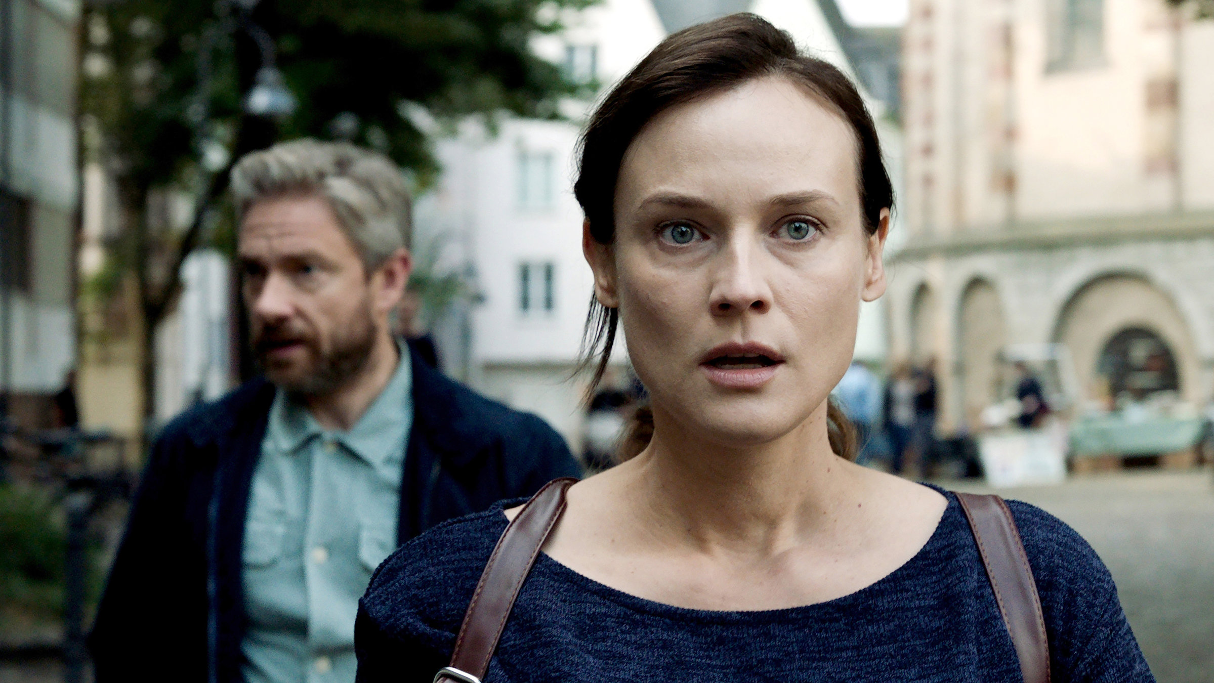 "Die Agentin": Mit erschrockenem Gesichtsausdruck und leicht erstarrt, blickt Rachel (Diane Kruger) nach vorne aus dem Bild, während dahinter Thomas Hirsch (Martin Freeman) etwas seitlich von ihr zu beobachten scheint.