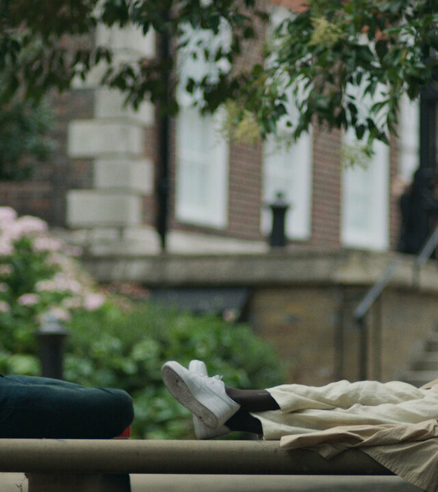 "Alice & Jack - Zu zweit": Jack (Domhnall Gleeson) sitzt auf einer Steinbank in einem Park. Ihm gegenüber sitzt Alice (Andrea Riseborough). Sie hat die Beine auf die Bank gelegt und schaut ihn an. Beide wirken ins Gespräch vertieft.