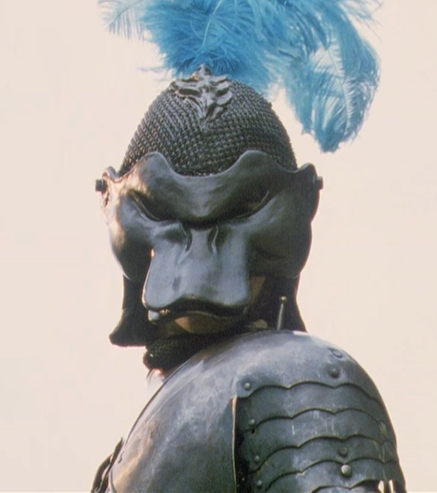 "Prinzessin Fantaghirò - Teil 2": Nahaufnahme von Prinzessin Fantaghirò (Alessandra Martines) in Ritterrüstung mit Helm. Sie blickt seitlich über die Schulter in Richtung Kamera. Auf dem Helm steckt ein blauer Federbusch.