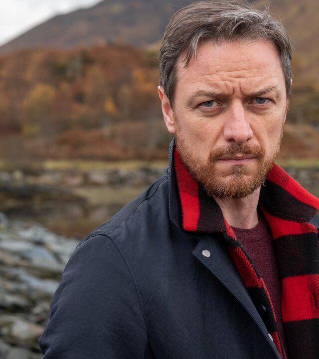 "Vermisst in den Highlands": Edmond Murray (James McAvoy) steht vor einem herbstlichen schottischen Gewässer, einem Loch, und blickt entschlossen nach vorne.