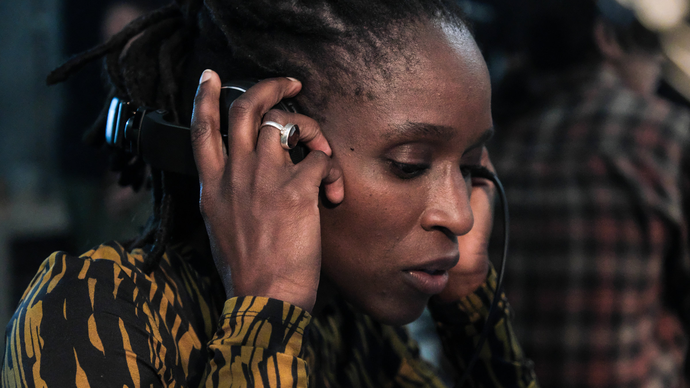 "Der Schwarm Folge 7": Die Astrophysikerin Samantha Crowe (Sharon Duncan-Brewster) trägt Kopfhörer, die sie mit beiden Händen auf ihre Ohren drückt. Sie schaut konzentriert zu Boden.