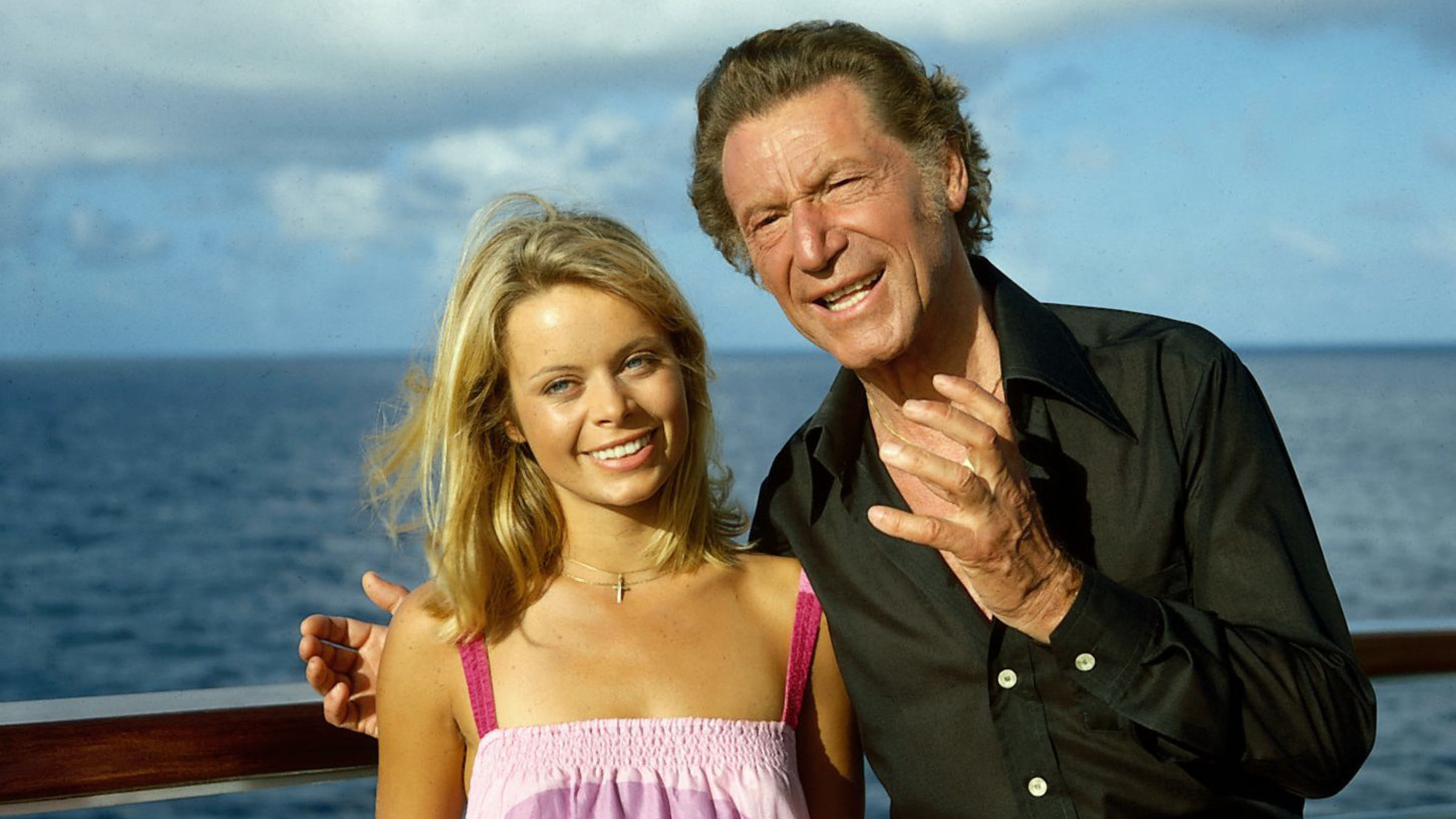 "Das Traumschiff - Liebe für Alice: Betsy und der Schlagerstar: Der Juwelendieb": Herr Eschenbach (Josef Meinrad) und seine Tochter Alice (Miroslava Safrankova) stehen auf dem Schiffsdeck. Herr Eschenbach legt seinen Arm um Alice. Beide lächeln und Herr Eschenbach scheint Alice etwas zu erklären.