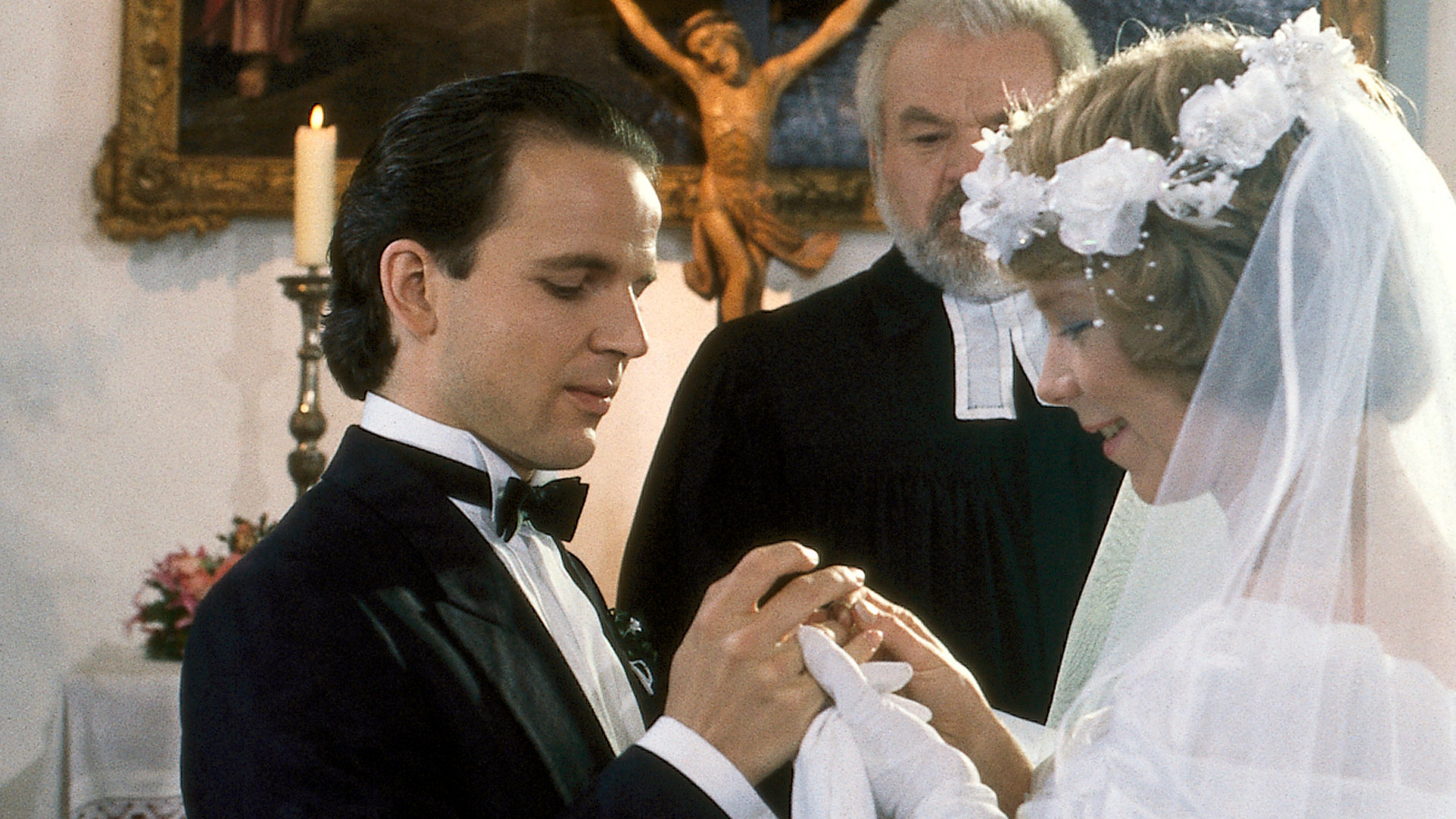 "Die Drombuschs - Die Gretchenfrage": In einer Kapelle stehen Chris (Mick Werup) und Tina (Marion Kracht) in Hochzeitskleidung und werden getraut.
