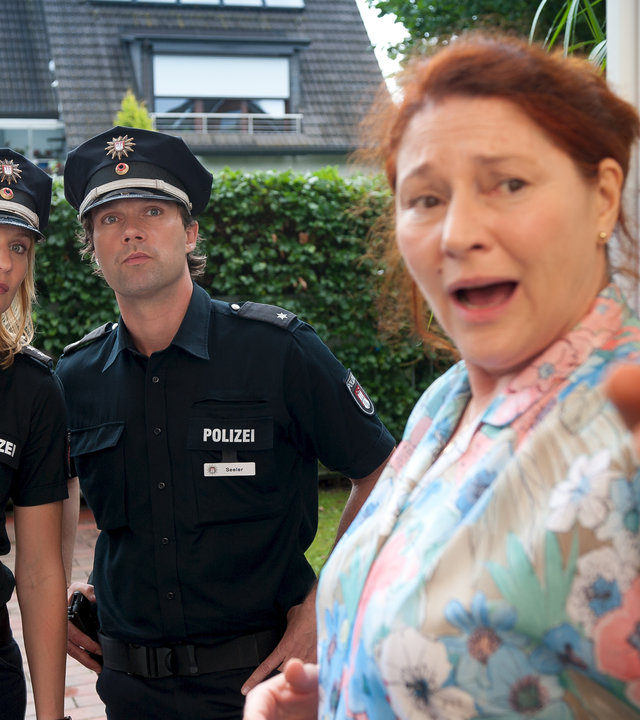 "Notruf Hafenkante - Dummer August": Frau Gradka (Wieslawa Wesolowska) hat die Polizei gerufen und zeigt Melanie (Sanna Englund) und Mattes (Matthias Schloo) an der Wohnungstür wo es lang geht.