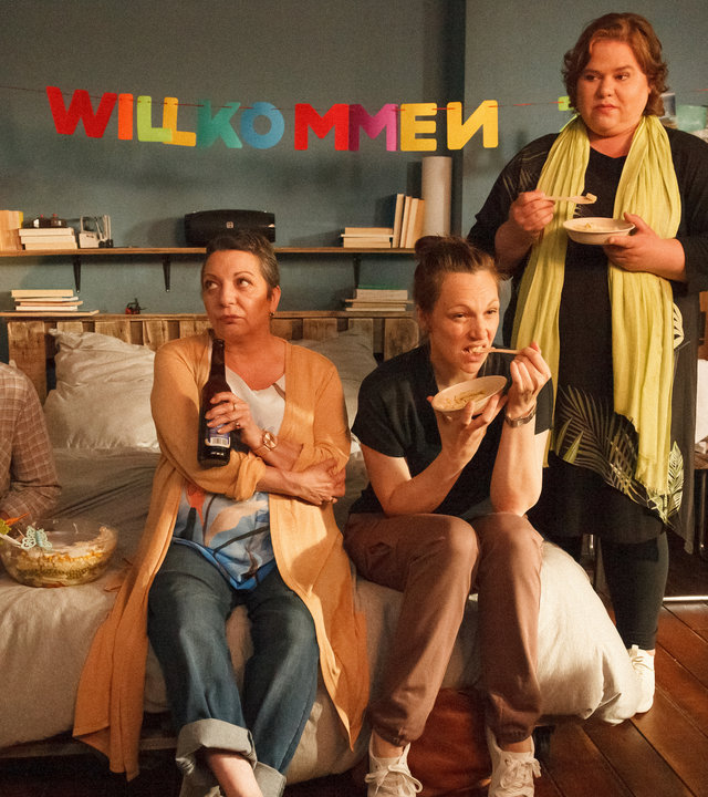 "Ich dich auch! - Der Schichtsalat": Jákup (Rolf Berg) und Marion (Manon Straché) sitzen mit Bier in der Hand auf dem Bett von Yannik. Claudia (Charlotte Bohning) sitzt daneben und kaut angespannt auf Besteck herum. Elli (Nadine Wrietz) steht am Bett und schaut genervt. Keiner sieht einem anderen in die Augen.