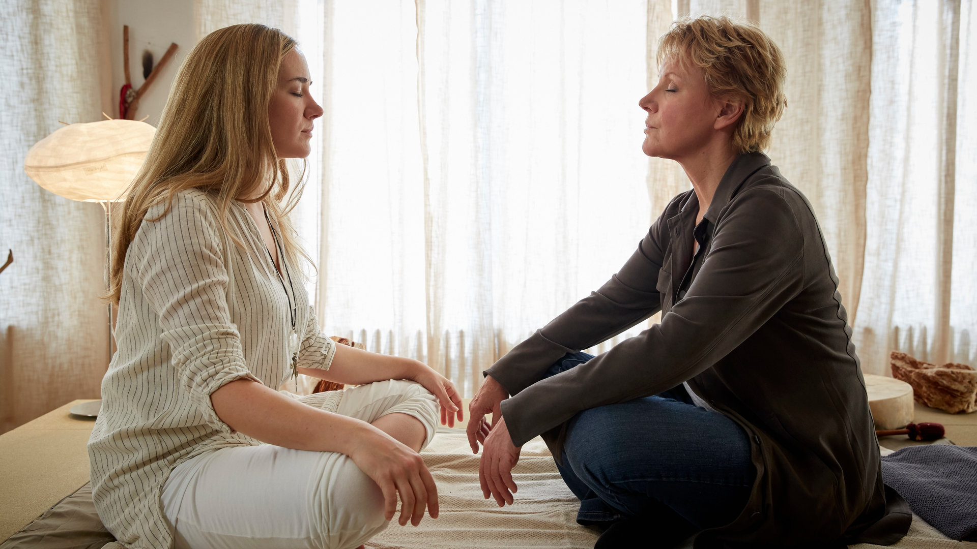 "Marie Brand und die rastlosen Seelen": Marie Brand (Mariele Millowitsch) und Kyra (Annina Hellenthal) sind im Behandlungsraum der schamanischen Praxis. Sie sitzen sich im Schneidersitz mit geschlossenen Augen gegenüber.