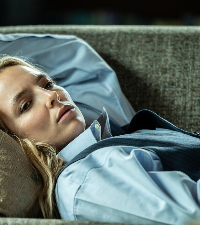 "Killing Eve - Ein Regenbogen in beigen Stiefeln": Villanelle (Jodie Comer) liegt auf einer Couch und schaut betrübt in die Ferne.