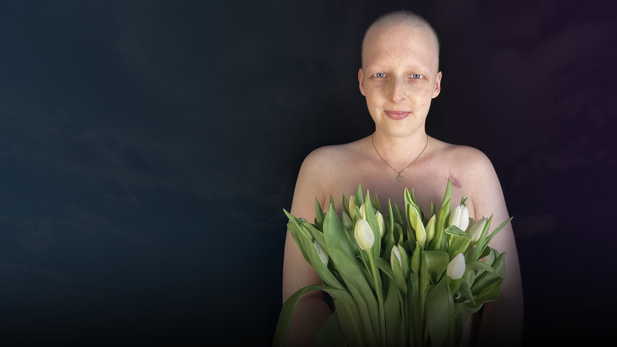 "37°Leben: Krebskrank und Kinderwunsch": Sarah steht vor schwarzem Hintergrund und schaut lächelnd in die Kamera. Vor sich hält sie einen Strauß weißer Tulpen.