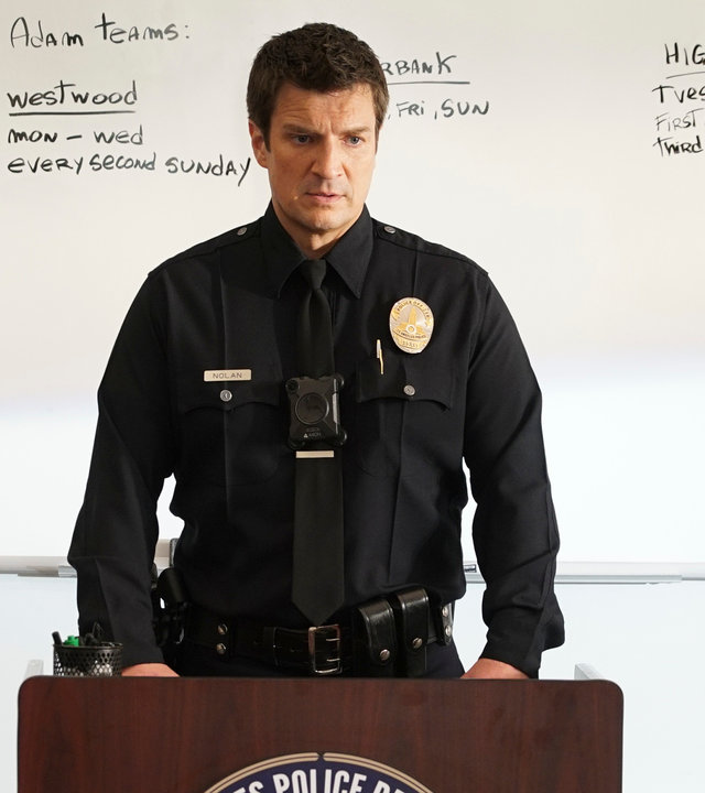 "The Rookie - Die Versuchung": Officer John Nolan (Nathan Fillion) steht vor einem Rednerpult. Und blickt in die Richtung seiner zuhörenden Kollegen. Im Hintergrund ein Whiteboard mit handschriftlichen Erörterungen.