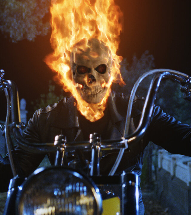 "Ghost Rider": Johnny Blaze (Nicolas Cage) fährt in Gestalt des Ghost Riders mit einem Motorrad, während sein Kopf von Flammen umgeben ist.