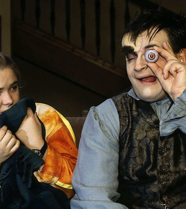 "Sprechstunde bei Dr. Frankenstein": Lenni (Michael Trischan) und Franzi (Fritzi Eichhorn) sitzen nebeneinander auf dem Sofa. Lenni hält sich ein künstliches Auge vor sein Auge.