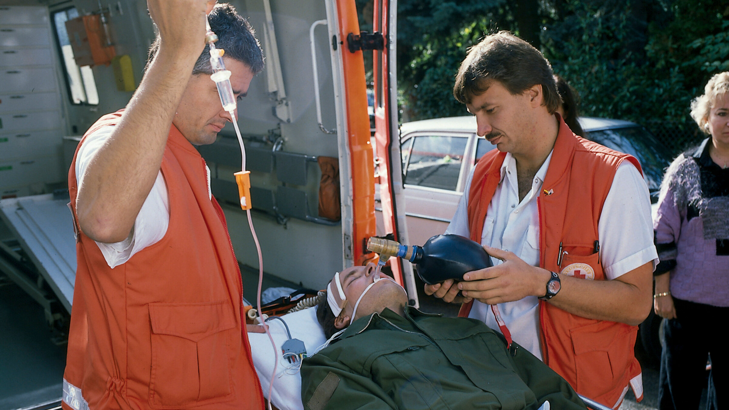"Diese Drombuschs - Der Makel": Chris (Mick Werup) liegt mit einem Kopfverband auf einer Trage und wird in den Krankenwagen geschoben. Links und rechts und von ihm stehen Sanitäter.