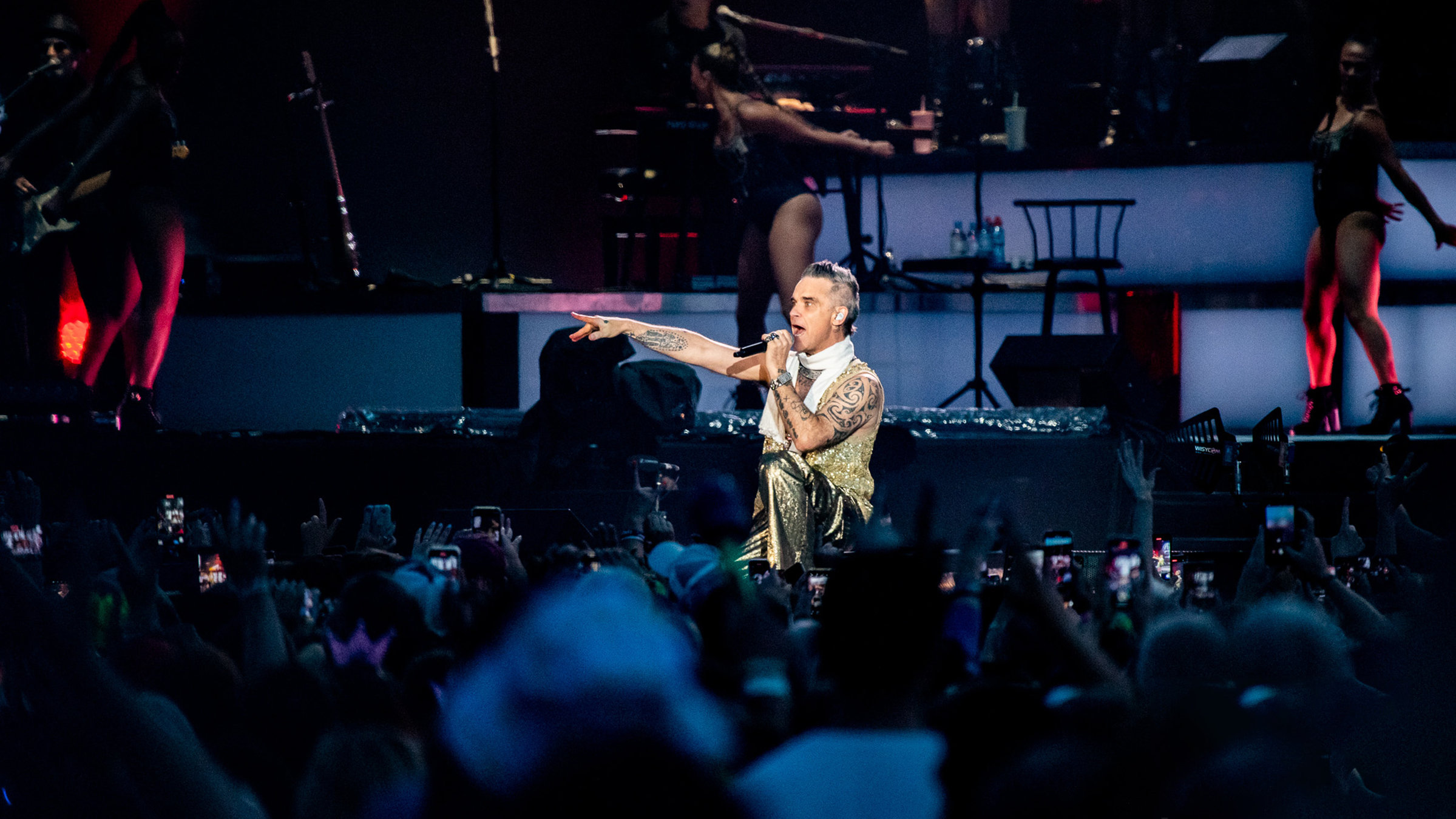 "Isle of Wight Festival 2023": Ein an den Armen tätowierter Mann in goldener Hose und goldener Weste kniet singend auf der Bühne. In der linken Hand hält er Mikrofon, den anderen Arm hat er seitlich ausgestreckt, als ob er auf etwas zeigen würde.