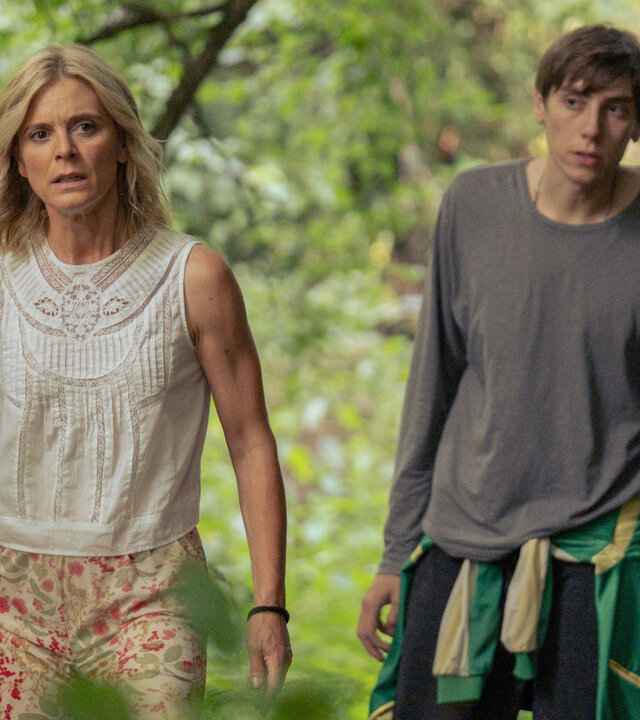 "Signora Volpe - Trug und Trüffel": Sylvia Fox (Emilia Fox) und Sasha Pavlenko (Alexander Arnold) gehen in einem Waldstück nebeneinander her. Sylvia hält eine Pistole in der rechten Hand.