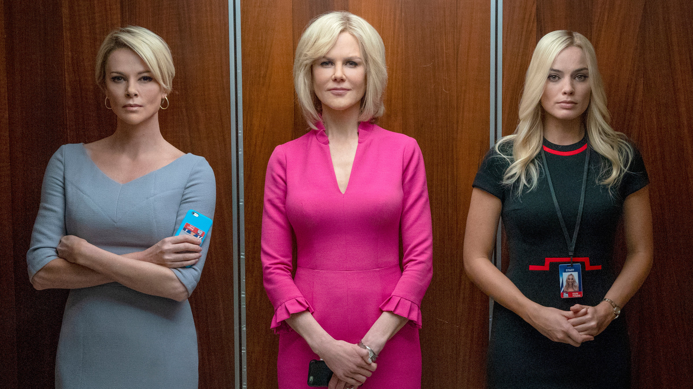 "Bombshell - Das Ende des Schweigens": Gretchen Carlson (Nicole Kidman), Megyn Kelly (Charlize Theron) und Kayla Pospisil (Margot Robbie) stehen nebeneinander in einem offenen Fahrstuhl und blicken den Betrachter an. Gretchen Carlson trägt ein auffälliges, pinkfarbenes Kleid.