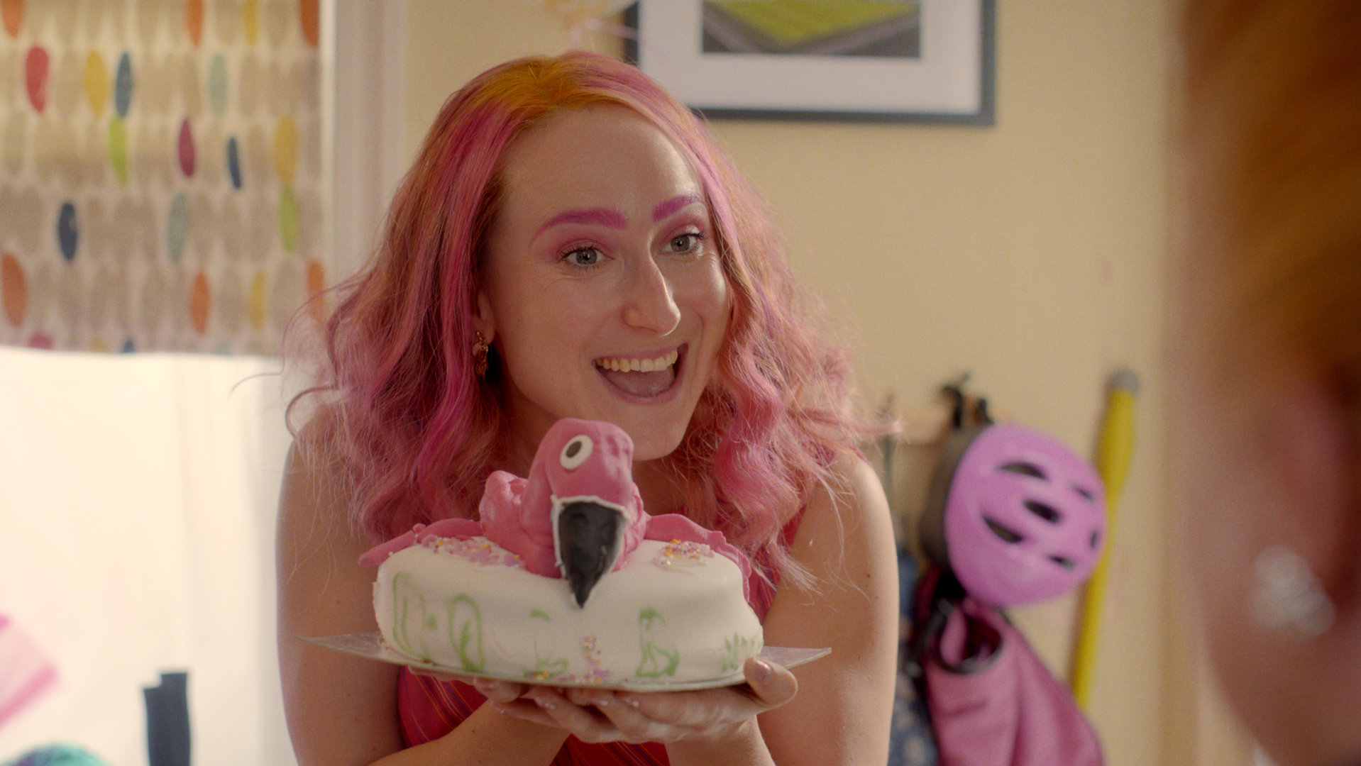 "Hullraisers - Erinnerungen": Toni (Leah Brotherhead) präsentiert stolz eine Torte mit einem pinken Flamingo darauf.