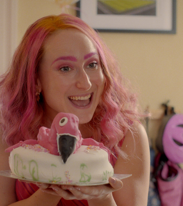 "Hullraisers - Erinnerungen": Toni (Leah Brotherhead) präsentiert stolz eine Torte mit einem pinken Flamingo darauf.