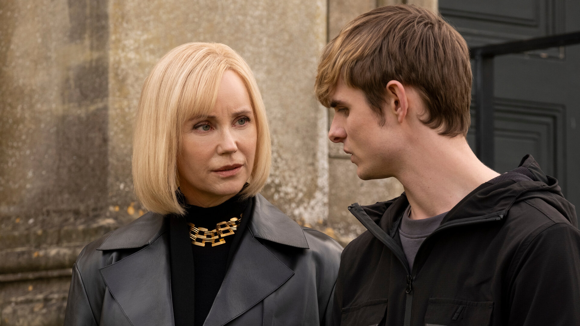 "Alex Rider - Zielscheibe": Mrs. Rothman (Sofia Helin) und Alex (Otto Farrant) stehen nebeneinander im Freien vor einer steinernen Wand. Sie blicken sich mit ernster Miene an.
